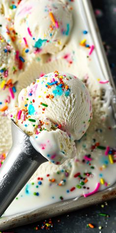 three scoops of ice cream with sprinkles in a metal pan on a table