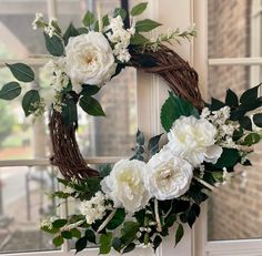 a wreath with white flowers and greenery on a window sill