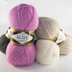 three balls of yarn sitting next to each other on a white surface with the words alze in gold