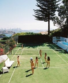 several women in bathing suits playing tennis on a grass court