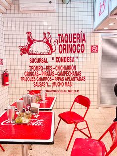 a red table and chairs in a room with white tile walls, tiled flooring and a sign that says taqueria ornoco