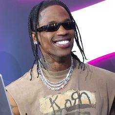 a man with dreadlocks smiles while looking at his laptop computer in front of him