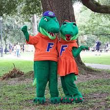 two people in alligator costumes standing next to a tree