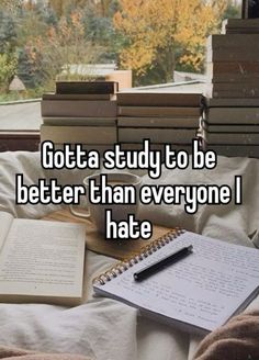 a pile of books sitting on top of a bed next to a notebook and pen