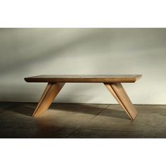 a wooden bench sitting on top of a cement floor in front of a white wall