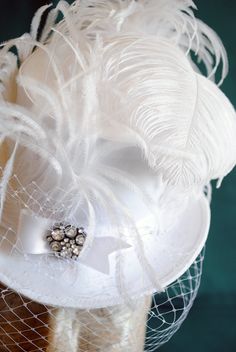 This gorgeous lady's mini top hat is covered with amazing white velvet or thick white satin. It is adorned with white satin ribbon,one stunningly luscious white ostrich plum and a glorious rhinestone button. The whole is complete with delicate birdcage veil in white. An amazing top hat to complete your bridal wear! Choose your fabric preference between white velvet and white satin. Please contact me if you are interested in purchasing this design in another color combination. Measurements : heig Hat With Veil, Bridal Fascinator, Mini Top Hat, Birdcage Veil, Wedding Fascinators, Victorian Wedding, Fascinator Hat, Unique Purses, Mini Top