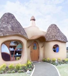 a house made out of clay with two round windows and a pathway leading to the front door