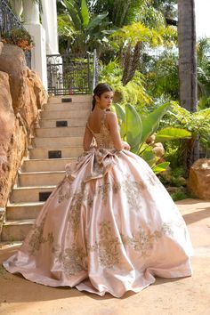 a woman in a ball gown standing on some steps with her hand on her hip