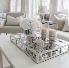 a tray with candles and flowers on top of a table in front of couches