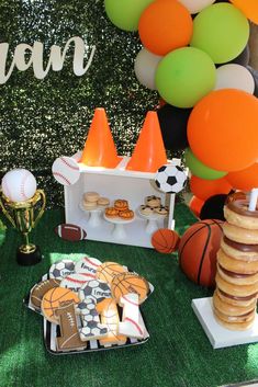 an outdoor sports themed birthday party with balloons and desserts on the grass, including cookies