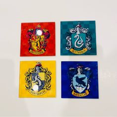 four harry potter house magnets on a white surface