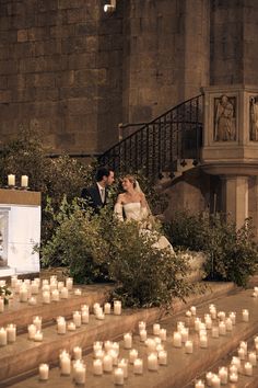 a bride and groom are sitting on the steps in front of candles at their wedding