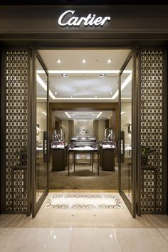 the entrance to a luxury jewelry store with its glass doors open and lights shining on it