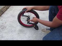 a man is fixing the spokes on a bicycle tire while crouching down to fix it