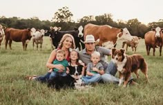 a man, woman and two children are sitting in the grass with cows