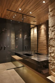 a modern bathroom with stone walls and flooring is pictured in this image, there are lights on the ceiling