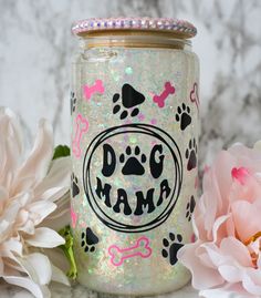 a glass jar with the word dog mama painted on it next to some pink flowers