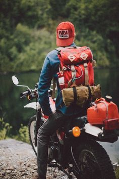 a man wearing a red hat and backpack standing next to a motorcycle