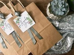 two brown paper bags with tags on them and some succulents in the background