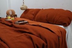 a bed with an orange comforter and some fruit on the table next to it