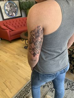 a woman with a tattoo on her arm standing in front of a couch and looking at the floor