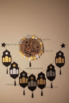 a clock with arabic writing on it hanging from a string in front of a wall