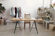 a desk with a laptop on it in a room filled with furniture and flowers,