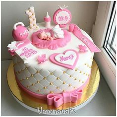 a baby's first birthday cake with pink and white decorations