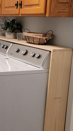 a washer and dryer in a small room with wooden cupboards on the wall