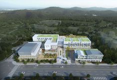 an aerial view of a building with green roofing and trees in the foreground