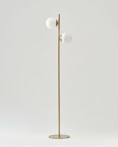 a brass floor lamp with three white balls on it