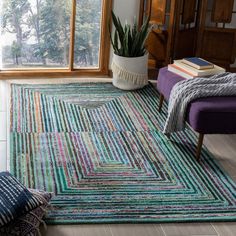 a living room area with a rug, chair and potted plant