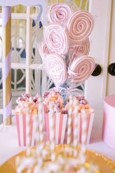 pink and white candy lollipops in striped paper wrappers on a table