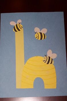 a paper cut out of the letter l with bees on it