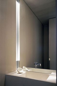 a bathroom sink sitting under a mirror in front of a wall mounted faucet