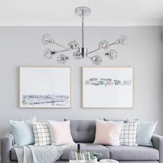 a living room with grey couches and pictures on the wall above them, along with two coffee tables