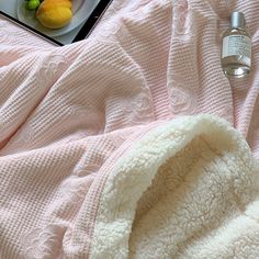 a pink blanket with a bottle of water and lemons on it next to an open laptop