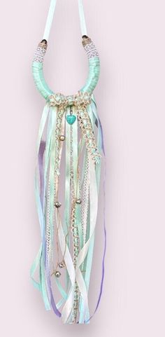 a necklace with beads and ribbons hanging from it's side on a pink wall