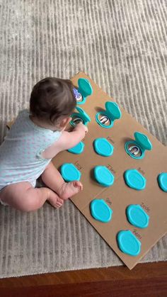 a baby sitting on the floor playing with blue buttons