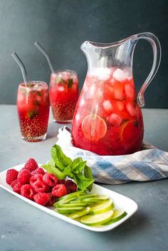 a pitcher and two glasses filled with watermelon, cucumber and mint