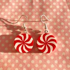 red and white candy cane earrings on pink polka dot fabric