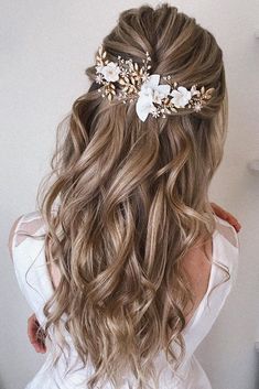 the back of a woman's head with long wavy hair and flowers in her hair