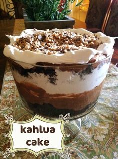 there is a dessert in the glass bowl on the table with words kahlua cake above it