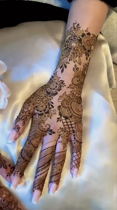 a woman's hand with henna on top of her arm and the bottom half of her hands