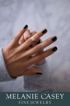 a woman's hand with black and white nail polish holding a ring on her finger