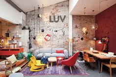 a living room filled with lots of furniture next to a wooden table and red brick wall