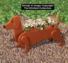 a wooden dachshund planter with flowers in it