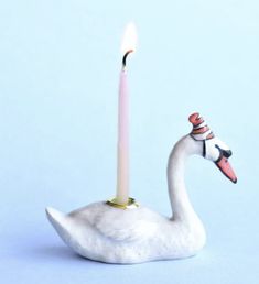 a white swan with a candle in its beak on a light blue background is shown