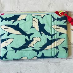 Handmade zipper pouch with a shark theme. Fun and colorful yet also useful. Perfect for carrying your phone and keys, make up, or utilize as a pencil case. The possibilities are endless. The pouch is quilted using a foam stabilizer giving it a more structured and secure feel. A colorful resin zipper with a ring pull keeps your belongings safe. While each pouch is one of a kind, they all deliver a punch of color to brighten your day.  The bag measures 9 x 6 inches. Nintendo Switch Shark Case, Shark Purse, Shark Pencil Case, Fish Pouch, Blue Zipper Pouch Case, Shark Lover, The Pouch, Purse Pouch, Brighten Your Day