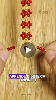 someone is making beaded bracelets with red beads on a wooden board and measuring the length